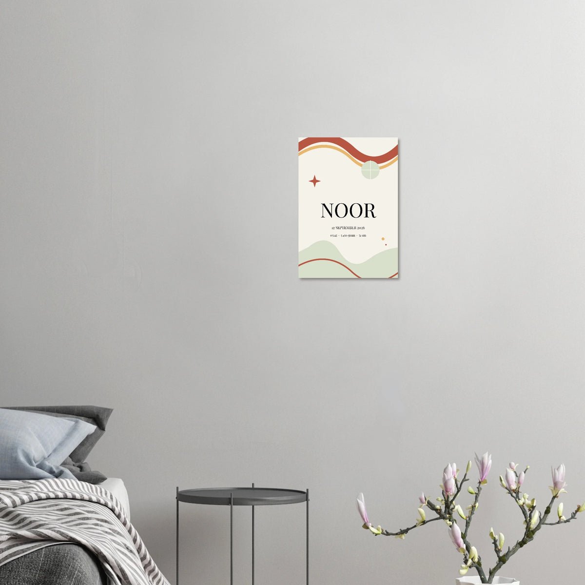 Geboorteposter Momentbogen met voorbeeldnaam Noor aan een grijze muur naast een bed